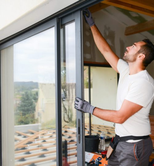 handsome young man installing bay window in a new house construction site